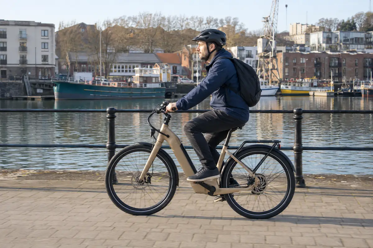 Cyclist riding a sand-coloured electric bicycle on Bristol harbourside