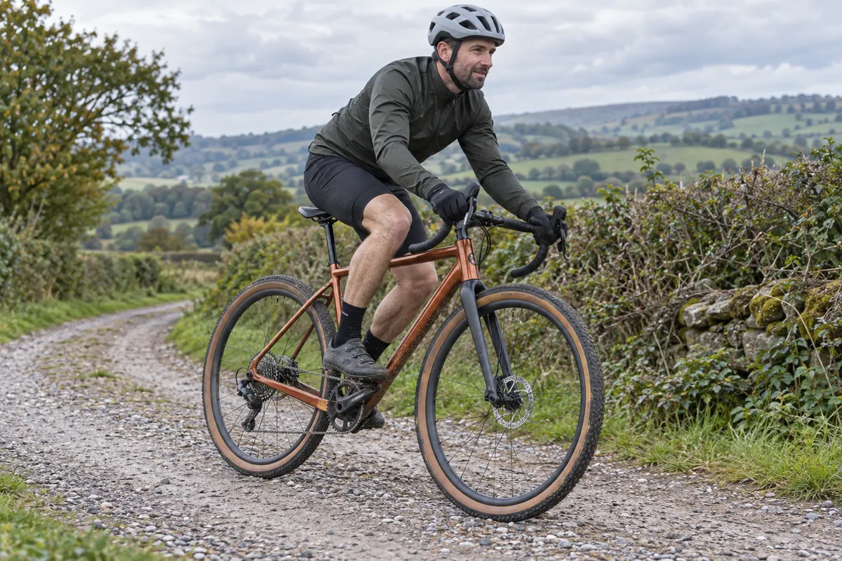 Helmeted cyclist riding a gravel bicycle on a woodland path