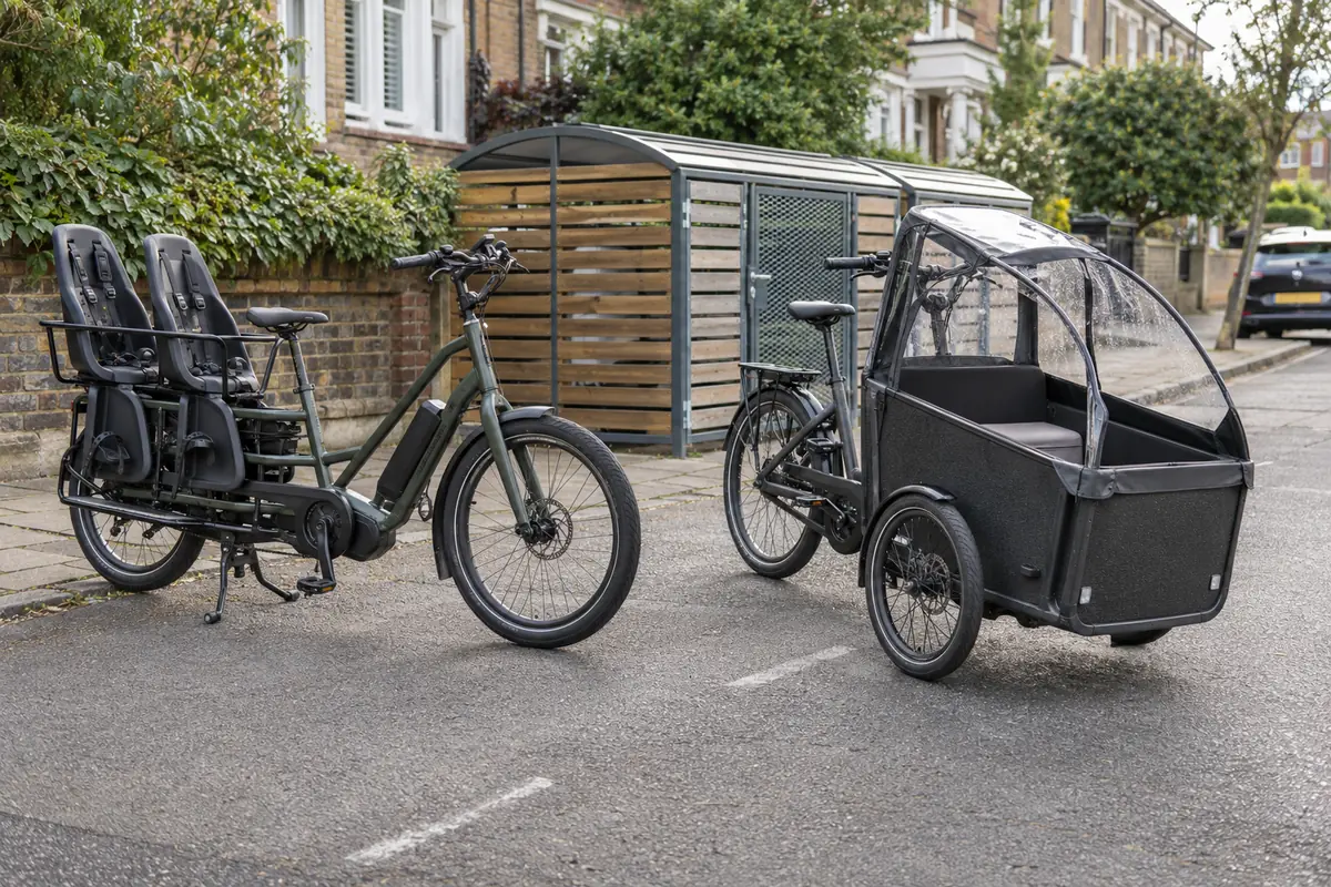 Unbranded long-tail and front-loading electric cargo bicycles parked on a British residential street