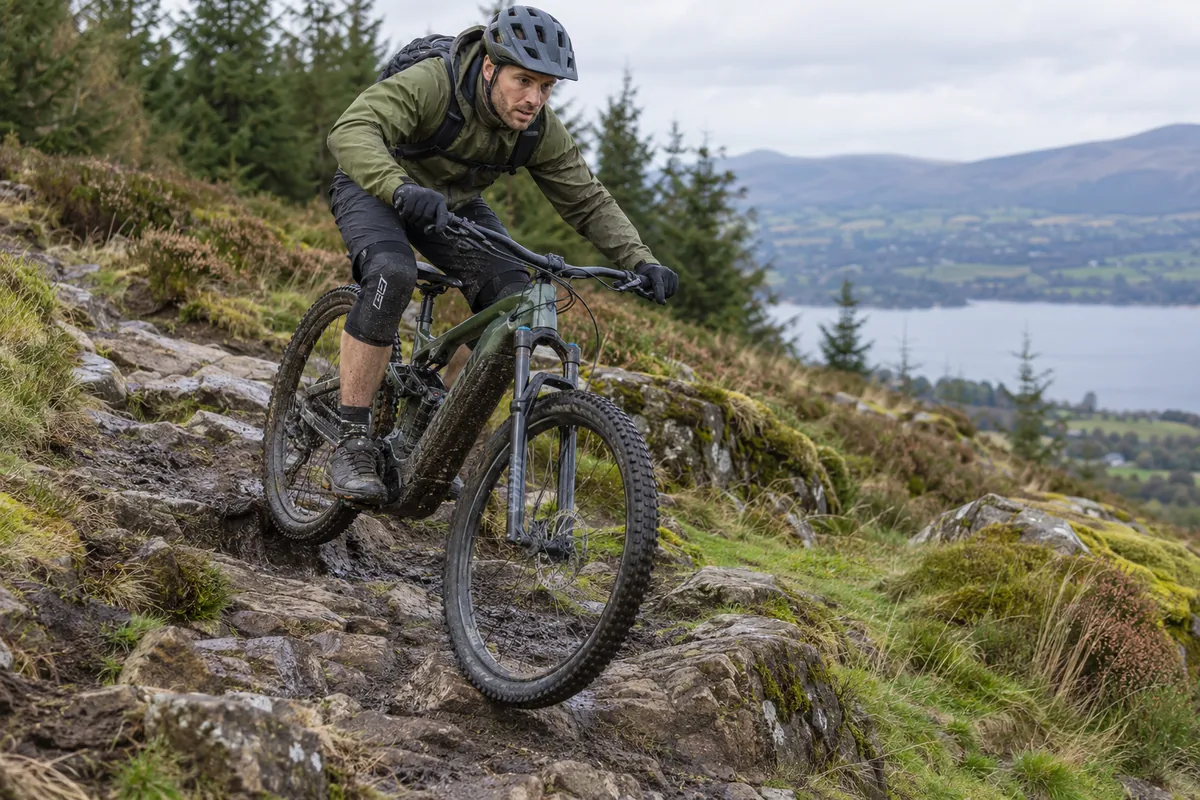 Rider descending a rocky trail on an unbranded full-suspension electric mountain bicycle